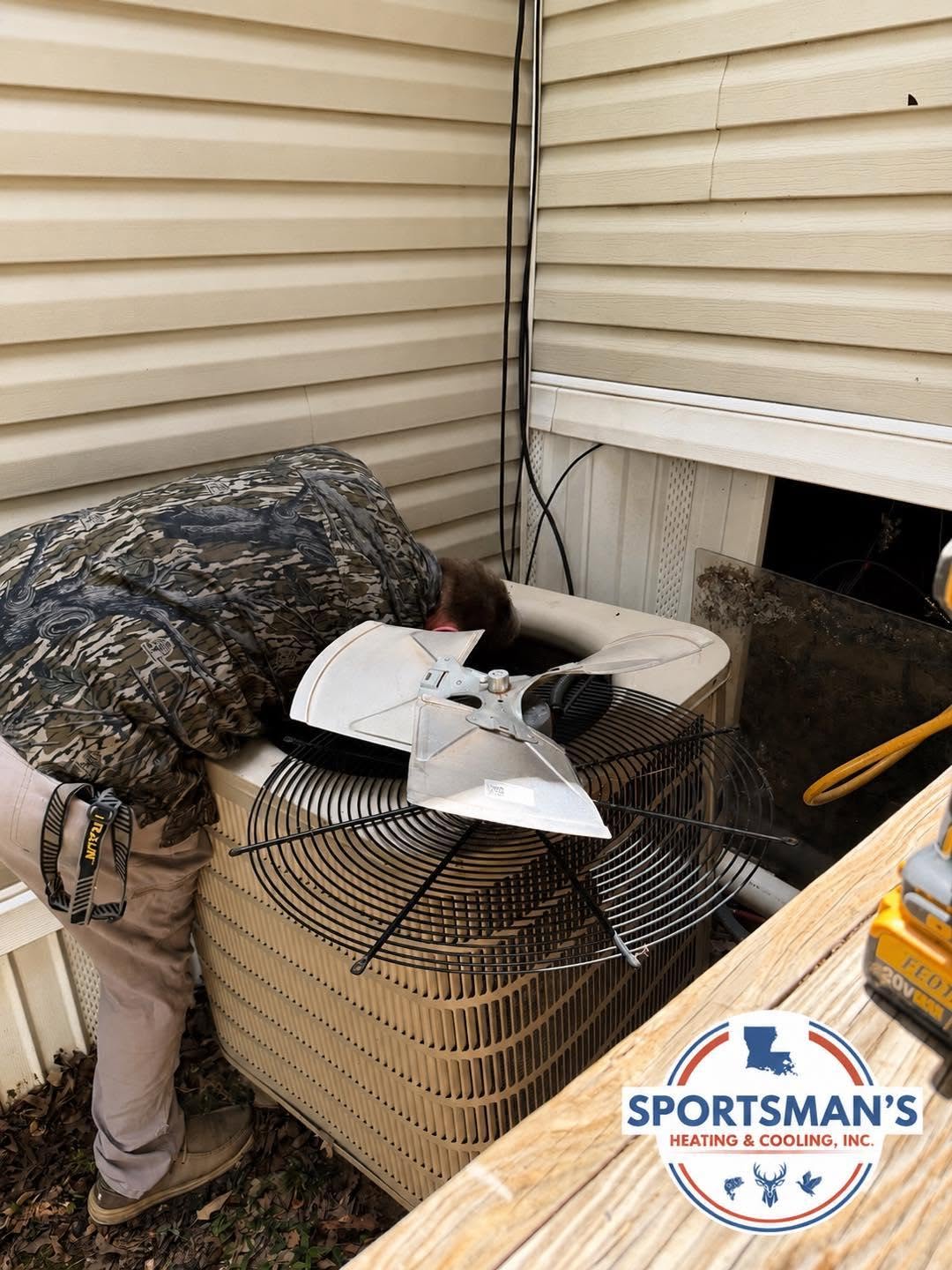Technician servicing the fan of an outdoor HVAC condenser